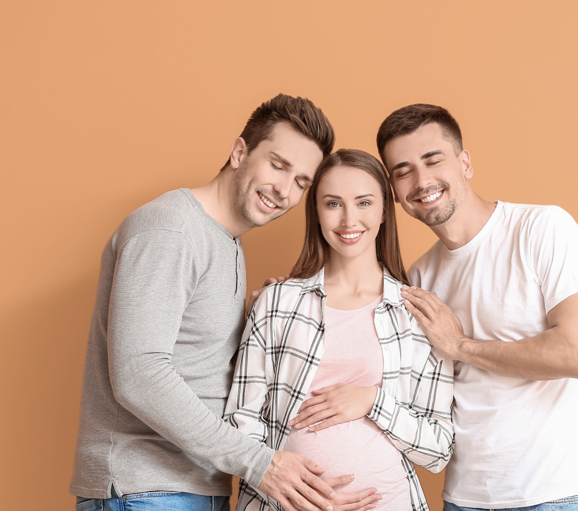 drei lächelnde personen halten den runden bauch der person, in der mitte.